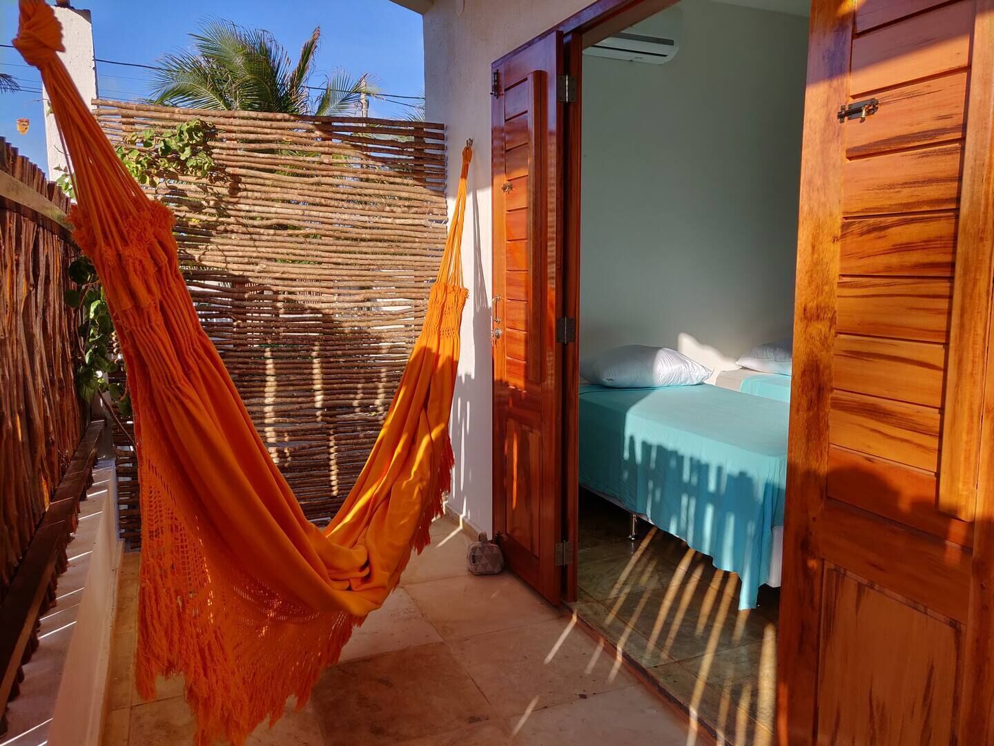 Um quarto com uma cama, uma rede e uma porta de madeira.