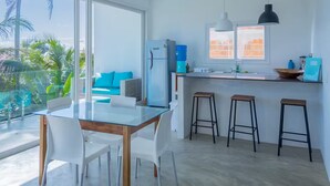 Una cucina moderna con un tavolo da pranzo in vetro, sedie bianche e un'area bar con sgabelli.