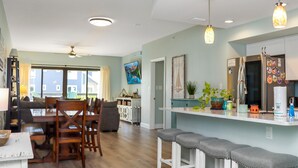 A modern kitchen with a stainless steel refrigerator, wooden dining table, and bar stools. - Club at Mexico Beach 1K Forgotten Cove (Port St. Joe)