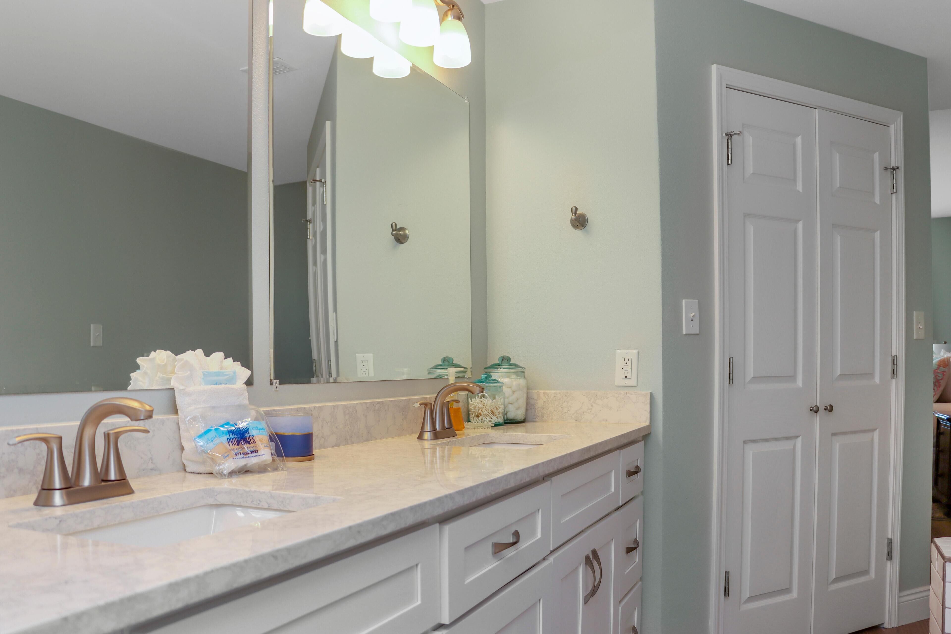 Une salle de bain avec un double lavabo, un grand miroir et une porte blanche.