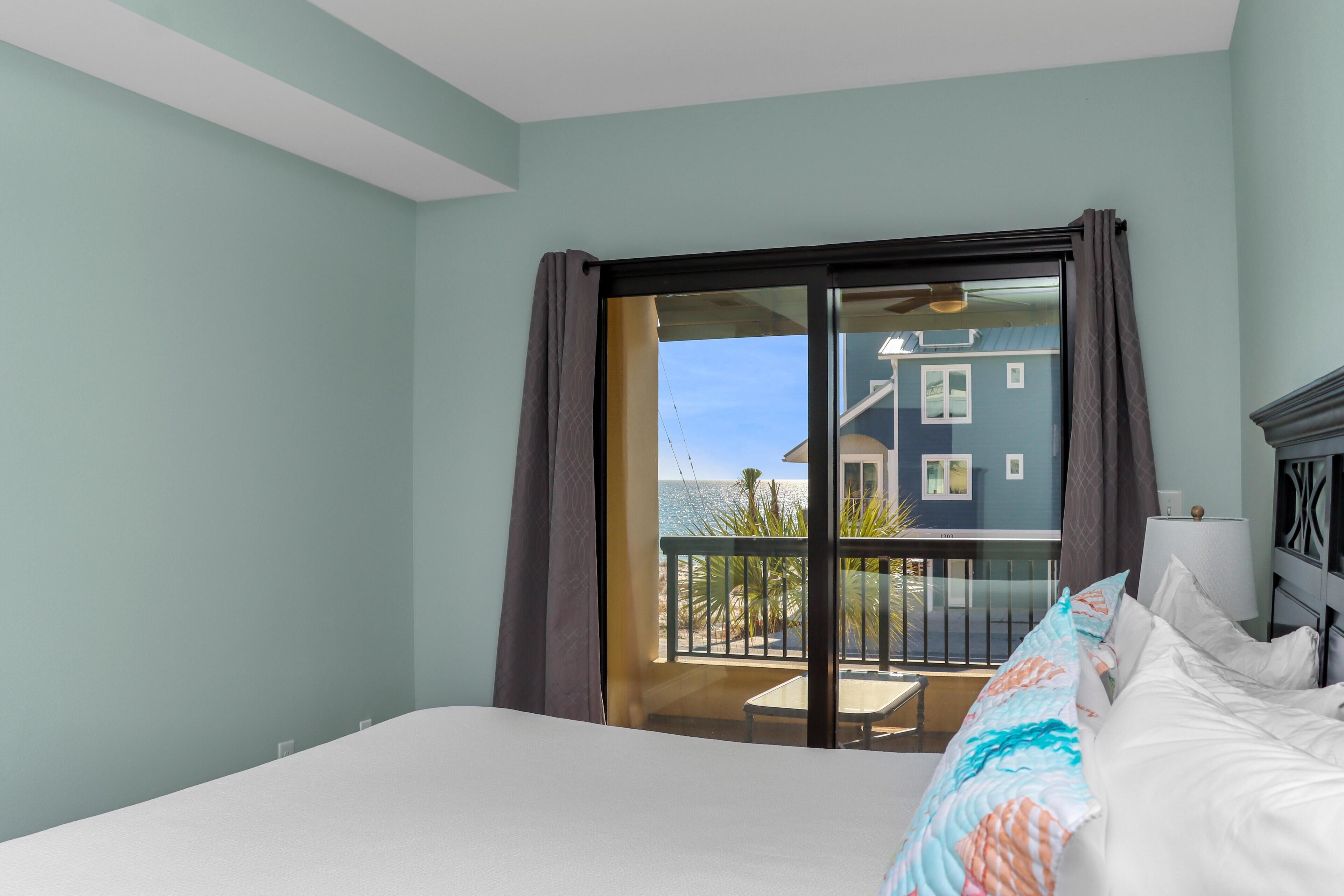Ein Hotelzimmer mit einem großen Bett, einem Balkon mit Meerblick und einer Schiebeglastür.