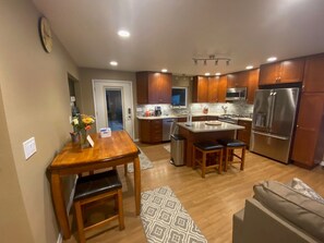 A modern kitchen with wooden cabinets, stainless steel appliances, and a central island with stools. - Rustic retreat with modern conveniences and great view (Anchorage)
