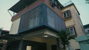 Una casa moderna de dos pisos con techo plano, balcón y entrada con reja.