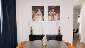 A dining area with a round table, four orange chairs, two wall-mounted lamps, and two framed pictures. - Modern Cozy Apartment, Free Parking, Wi-Fi, Near Dining and Downtown. (Chicago)