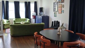 A modern living room with a green sofa, a dining table with chairs, and a TV. - Modern Cozy Apartment, Free Parking, Wi-Fi, Near Dining and Downtown. (Chicago)