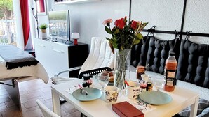 A dining area with a white table, black and white chairs, a vase with flowers, and a black sofa.