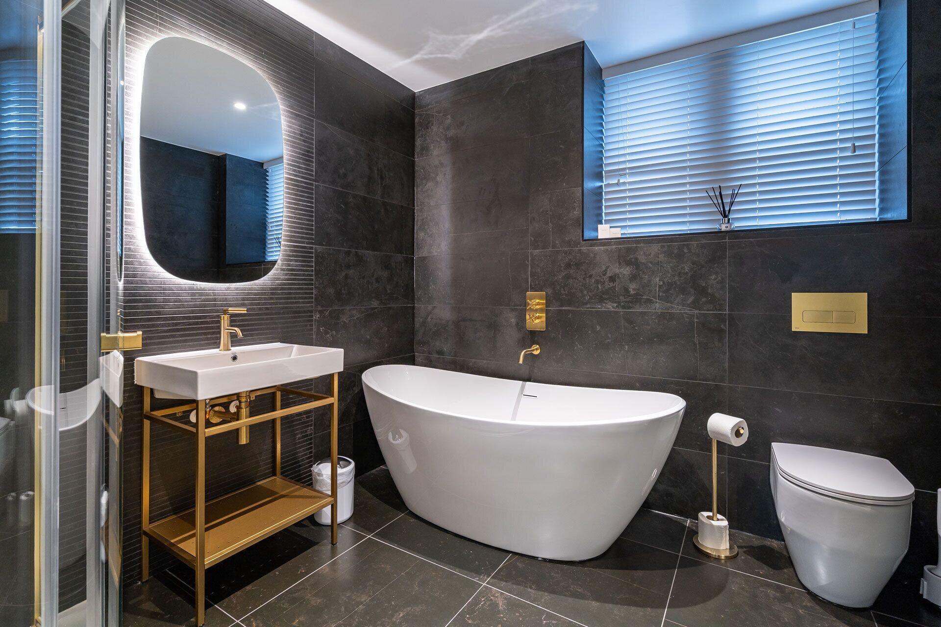 A modern bathroom with a freestanding bathtub, a vanity with a mirror, and a toilet.