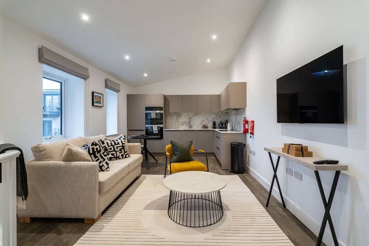 A compact living space with a sofa, a coffee table, a TV, and a kitchen area.