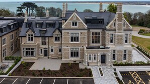 Un grand bâtiment en pierre, doté de nombreuses fenêtres et d’une cheminée imposante, situé pr ès d’une étendue d’eau.