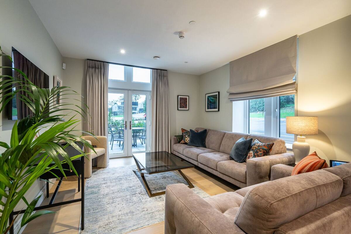 A modern living room with a sofa, coffee table, and a large window with curtains.