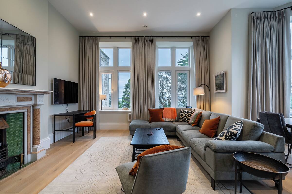 A modern living room with a fireplace, sofa, and a dining area.