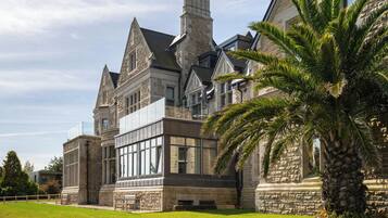 A large stone building with multiple chimneys and a large glass window.
