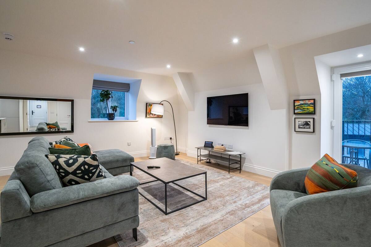 A modern living room with grey sofas, a coffee table, a flat-screen TV, and artwork on the walls.