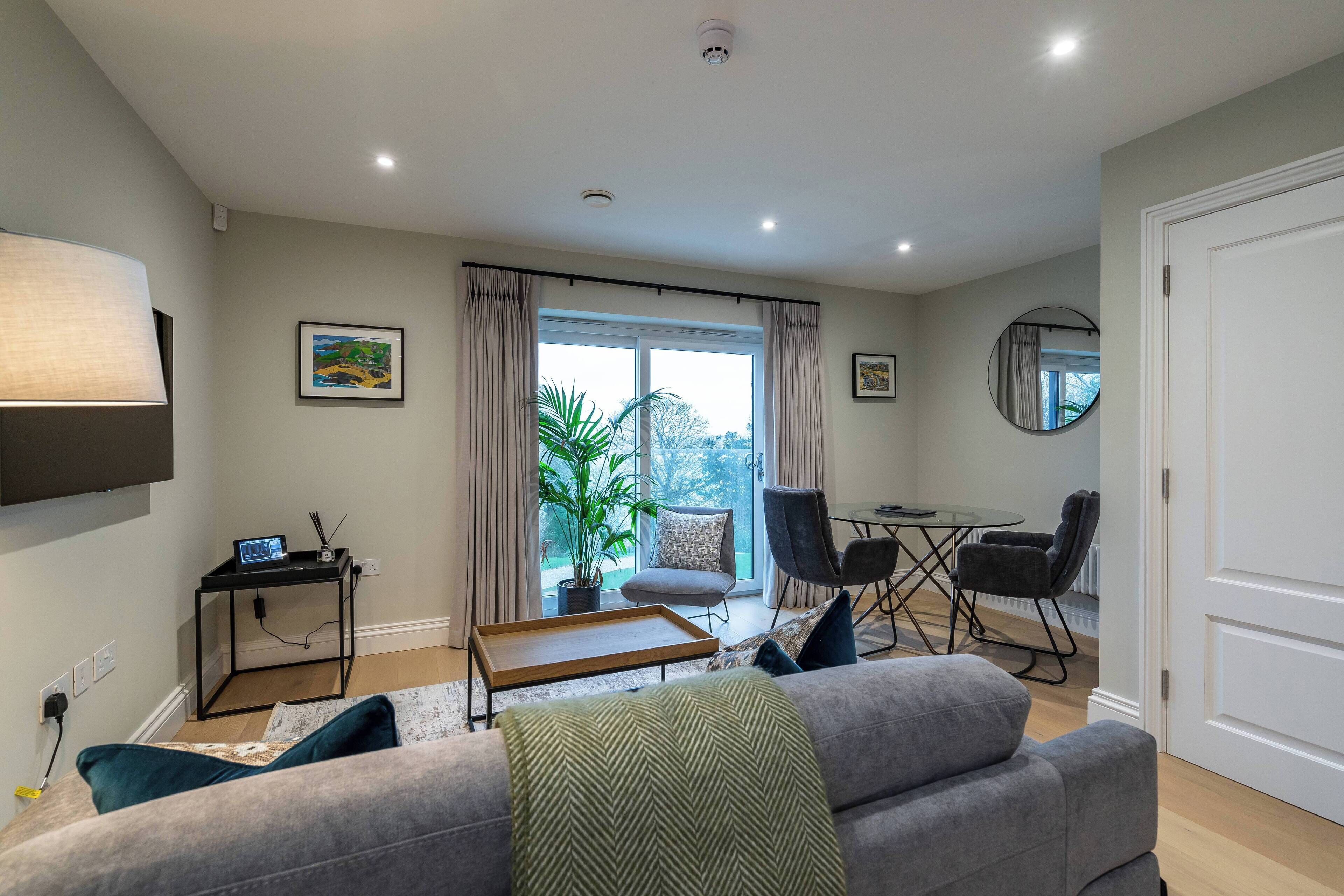 A modern living room with a sofa, a coffee table, a TV, and a dining area with chairs and a table.