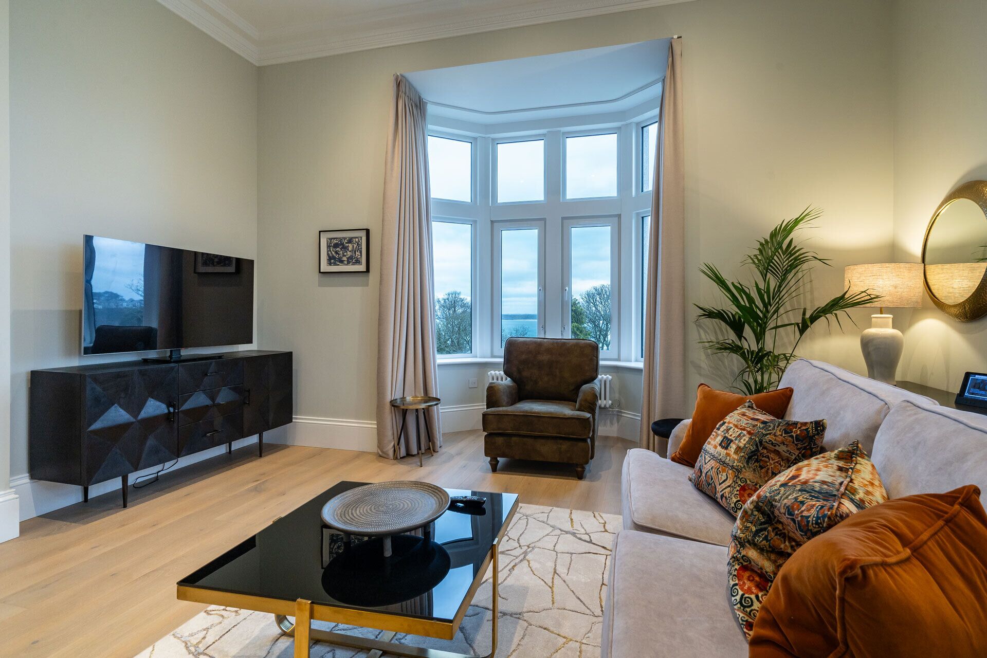 A living room with a sofa, armchair, TV, and a table with a lamp.