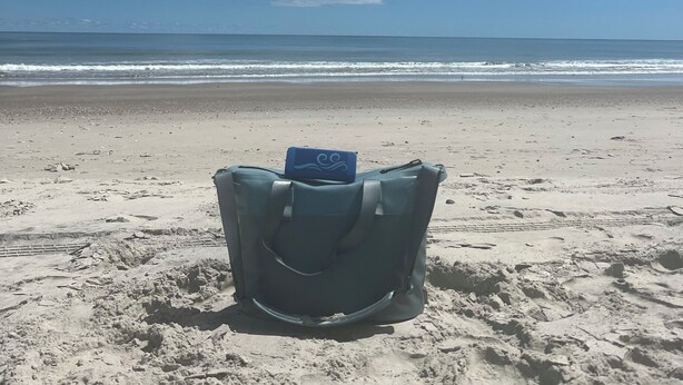 A beach chair with a blue object on it, facing the ocean. - Charming studio in lovely Emerald Isle with beach access (Emerald Isle)