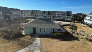 A residential building with a central entrance, multiple balconies, and a surrounding lawn. - Charming studio in lovely Emerald Isle with beach access (Emerald Isle)