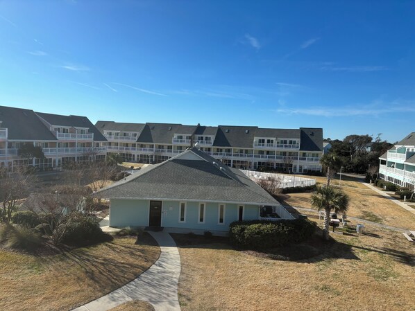 A residential building with a central entrance, multiple balconies, and a surrounding lawn. - Charming studio in lovely Emerald Isle with beach access (Emerald Isle)