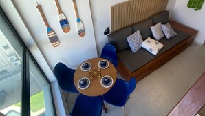 Un espacio de estar moderno con un sofá, sillas azules, una mesa de madera con cuatro tazas y objetos decorativos en la pared.