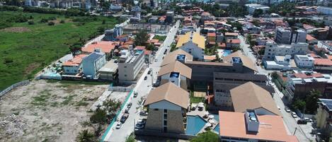 An aerial view of a coastal residential area with buildings, a swimming pool, and a beach.