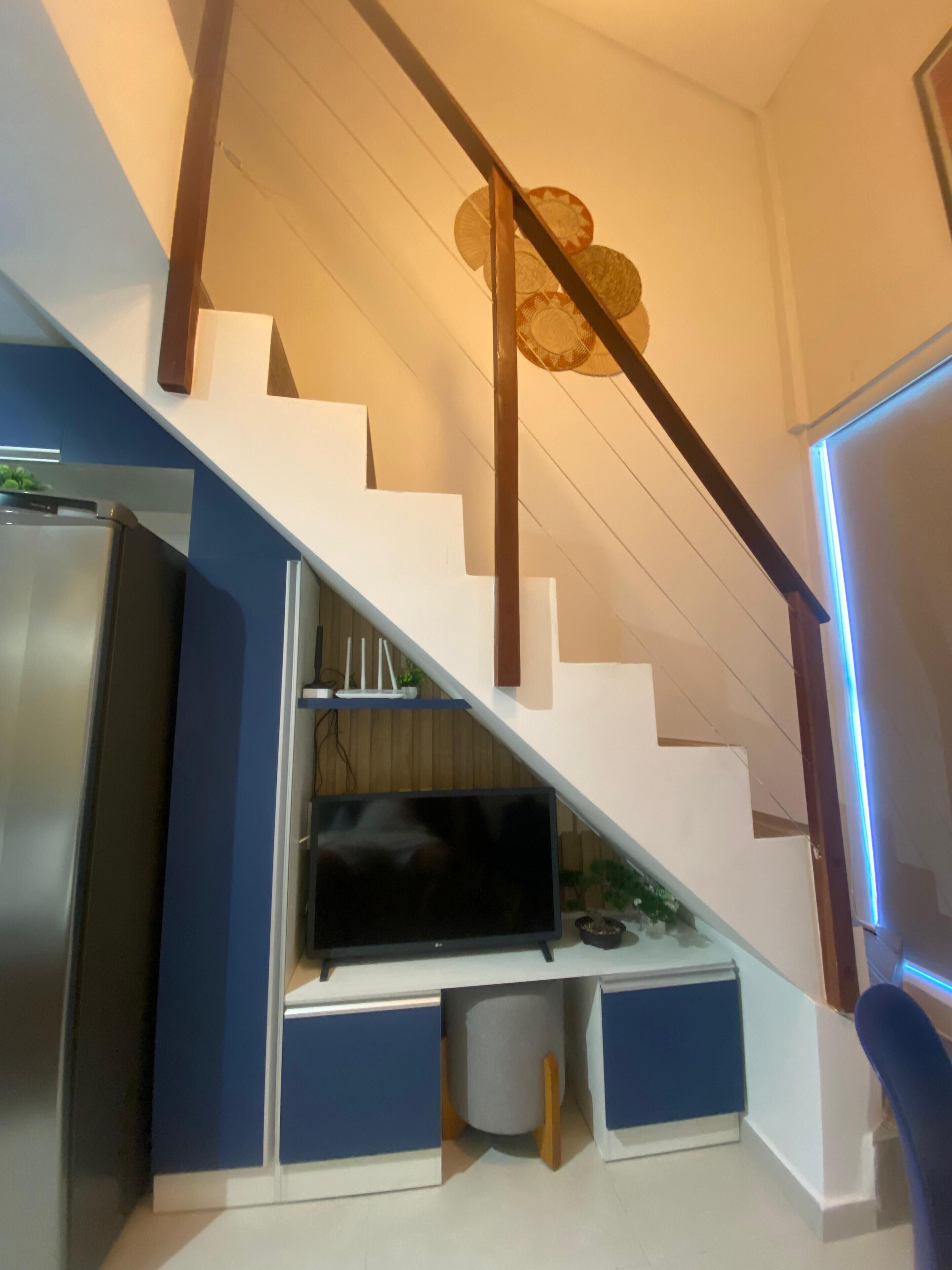 A modern staircase with a built-in entertainment unit, including a flat-screen TV and storage compartments.