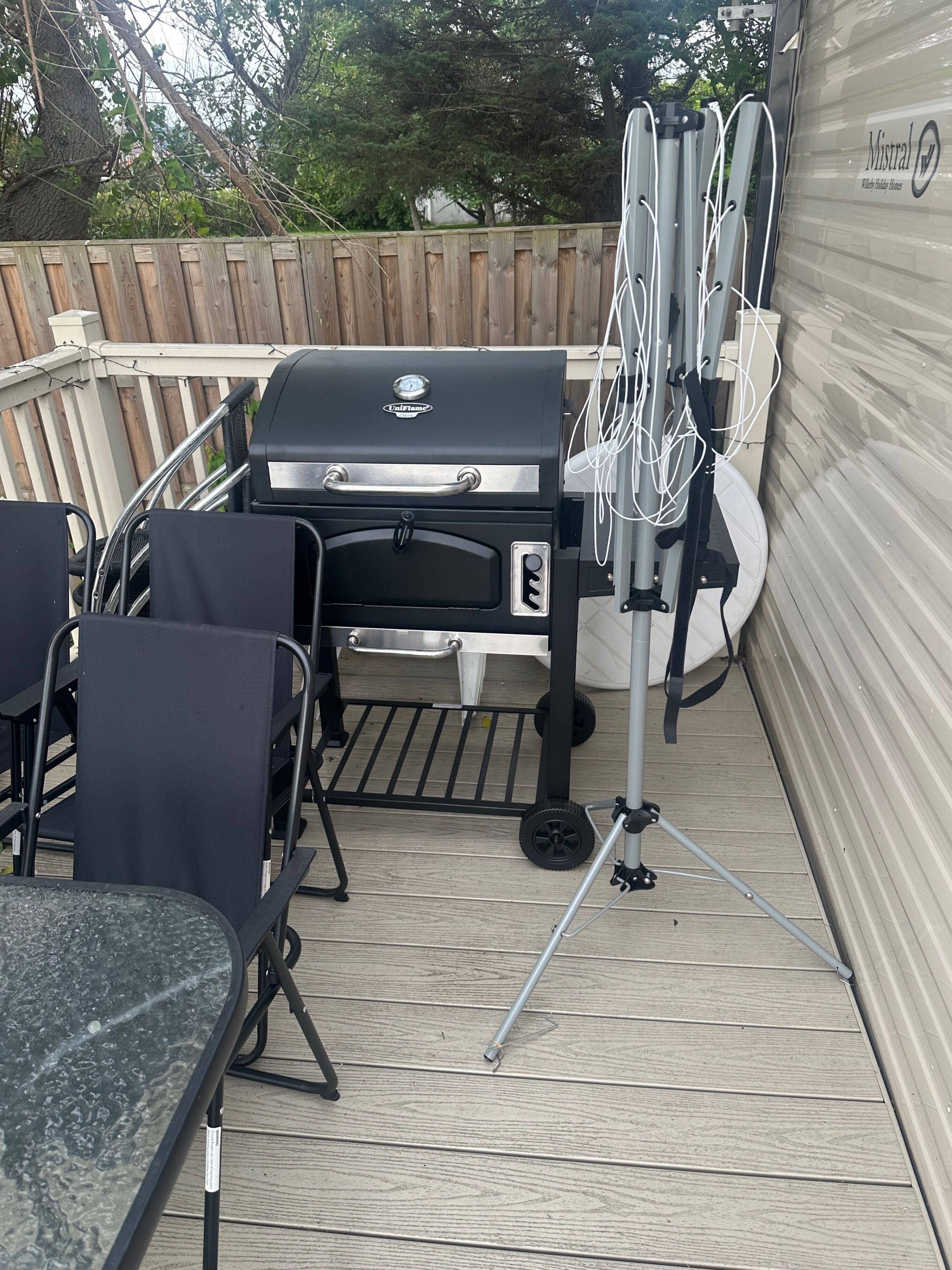 A patio with a grill, chairs, and a table.