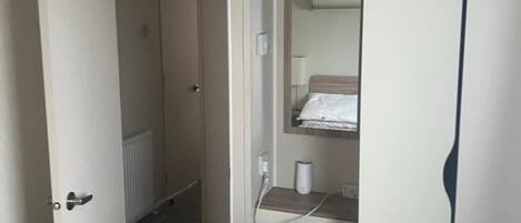 Ein Zimmer mit einem Bett, einem Kleiderschrank, einem Spiegel und einem durchgegangenen Tür erkennbaren Badezimmer.
