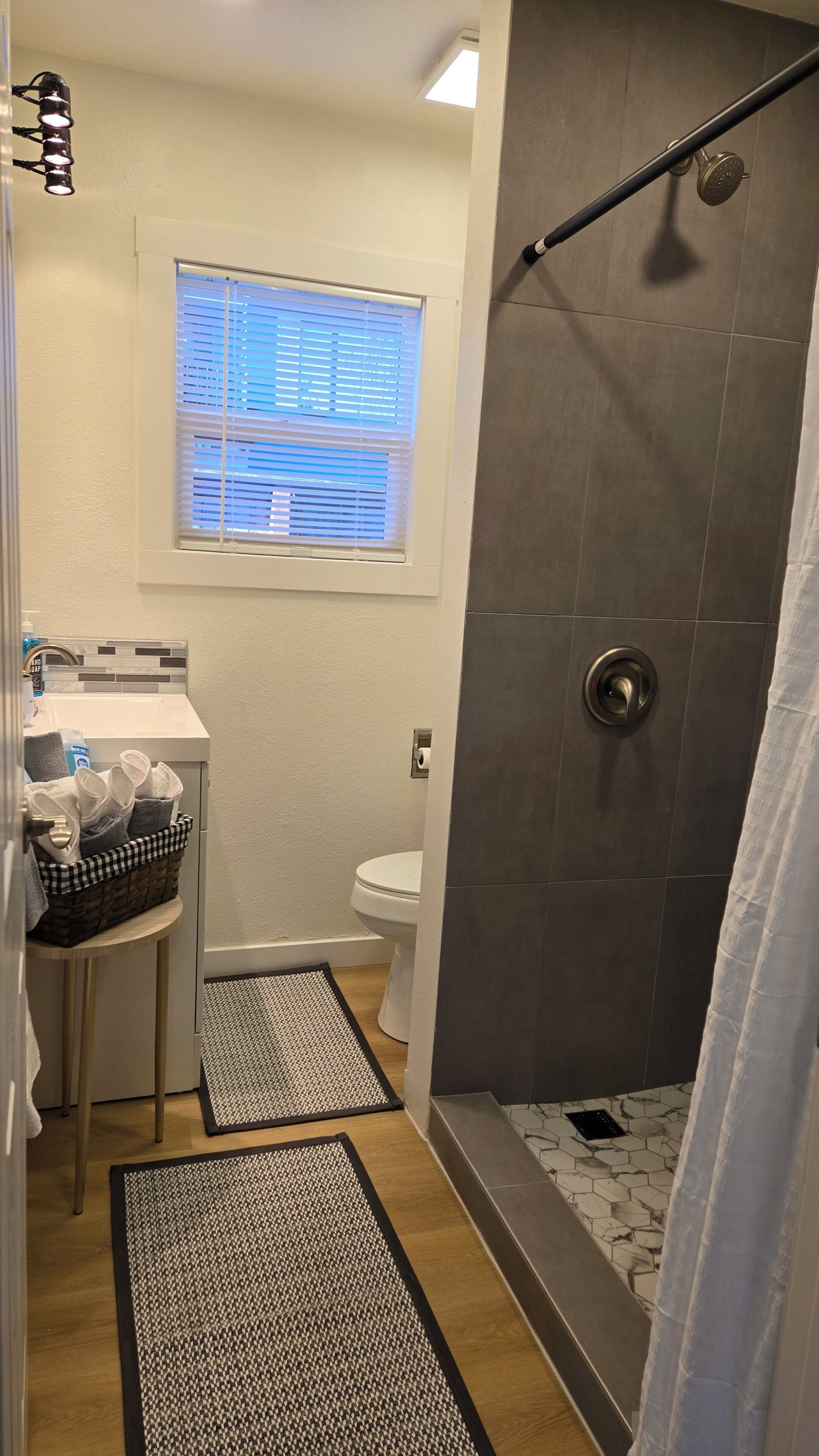 Une salle de bain équipée d’une douche, de toilettes, d’un lavabo et d’une fenêtre avec des stores.