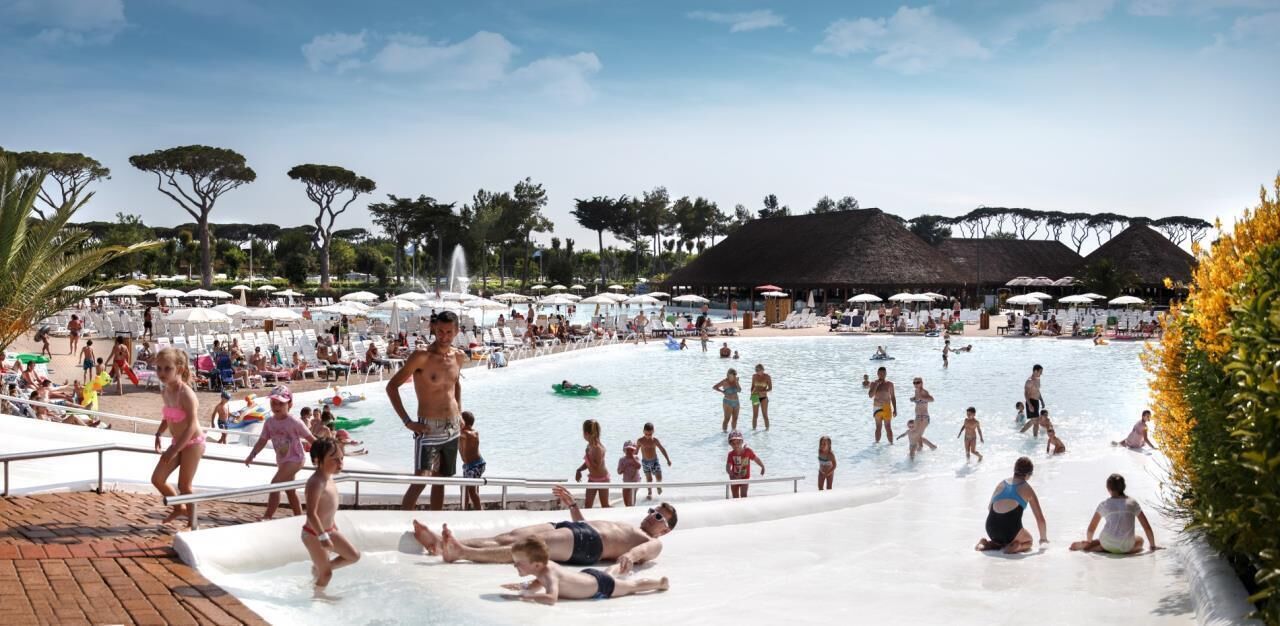 Un parque acuático con múltiples piscinas y toboganes, rodeado de sombrillas y árboles.