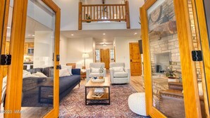 A spacious living room with a high ceiling, a wooden staircase, and a stone fireplace. - Luxurious 4-bedroom cabin with WiFi and AC in tranquil Show Low (Show Low)