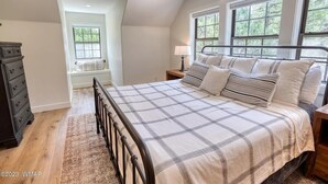 A bedroom with a large bed, a dresser, and a window with a view of trees. - Luxurious 4-bedroom cabin with WiFi and AC in tranquil Show Low (Show Low)