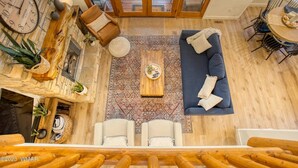 A spacious living area with a wooden coffee table, a blue sofa, and a stone wall clock. - Luxurious 4-bedroom cabin with WiFi and AC in tranquil Show Low (Show Low)
