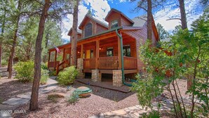 A log cabin with a porch, surrounded by trees and a stone pathway. - Luxurious 4-bedroom cabin with WiFi and AC in tranquil Show Low (Show Low)