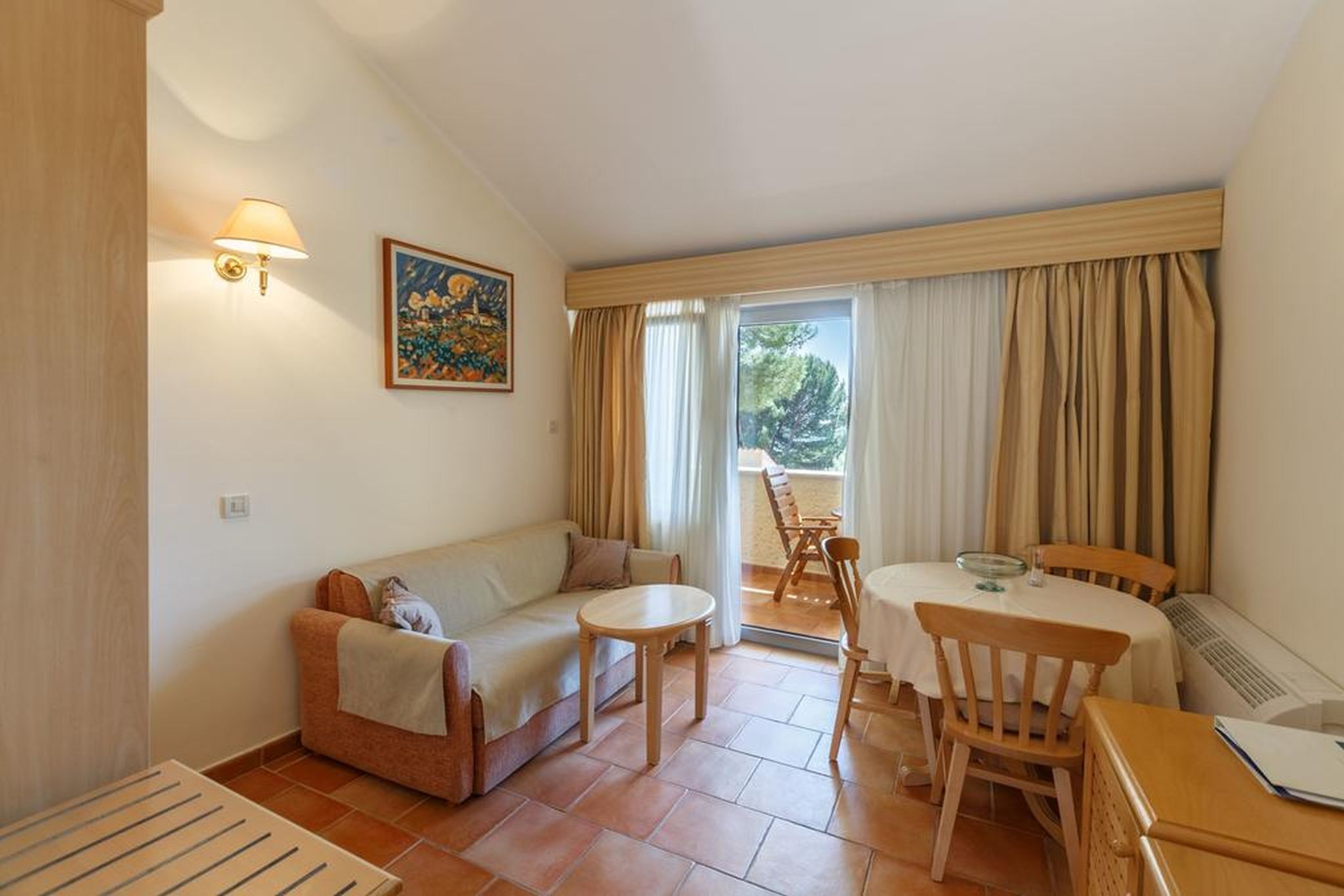 A cozy living room with a sofa, a small table, and a dining area with chairs and a table.