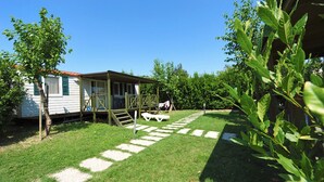 Een klein huis met een veranda, een overdekt terras en een geplaveid pad.