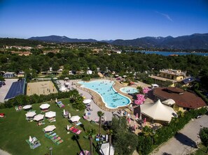 Vue aérienne d’un complexe hôtelier doté d’une grande piscine, de chaises longues et offrant une vue sur les montagnes et la mer environnantes.