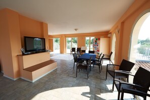 A spacious living area with a TV, a dining table, and chairs.