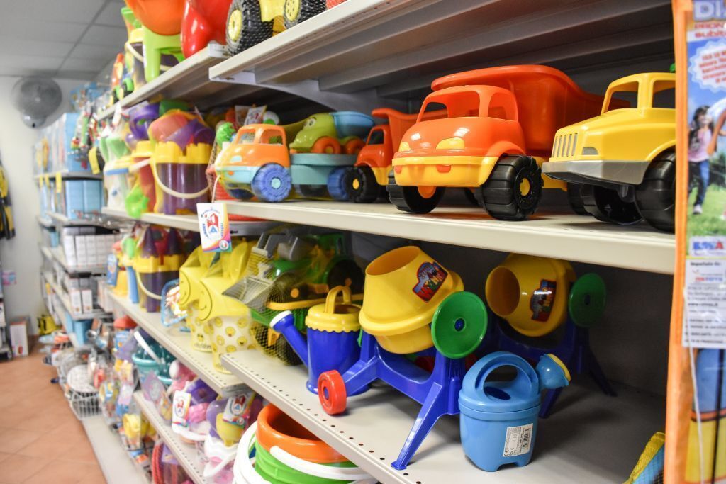 A shelf stocked with colorful toy vehicles and gardening tools.