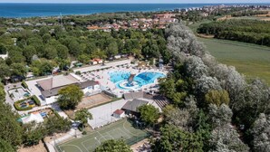 Vue aérienne d’un complexe hôtelier doté d’une grande piscine, de courts de tennis et offrant une vue sur la mer.