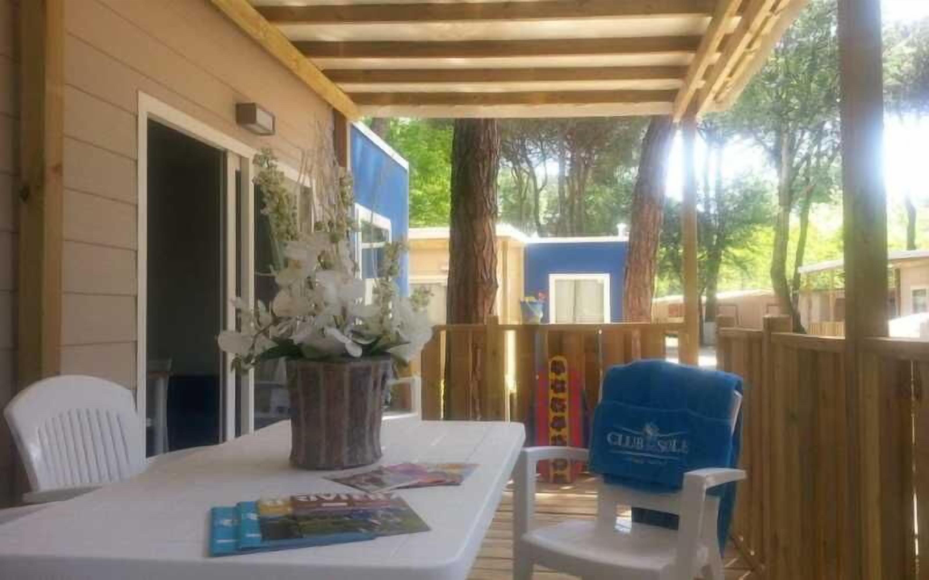 A covered patio with a table set for two, a chair, and a bag labeled "Club Sale".