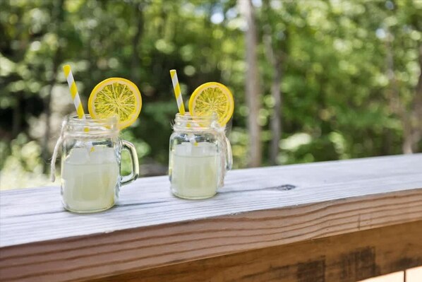 Two mason jars with straws and lemon slices on a wooden railing.
