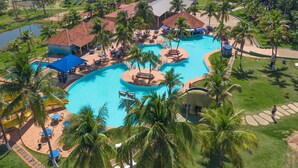 Un resort con diverse piscine, palme e sistemazioni per gli ospiti.