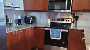 A modern kitchen with wooden cabinets, stainless steel appliances, and a granite countertop.