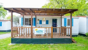 A mobile home with a wooden deck and a 'Happy Easy' sign.