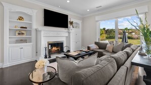 Ein Wohnzimmer mit Kamin, einer großen Couch und einem Fernseher an der Wand.