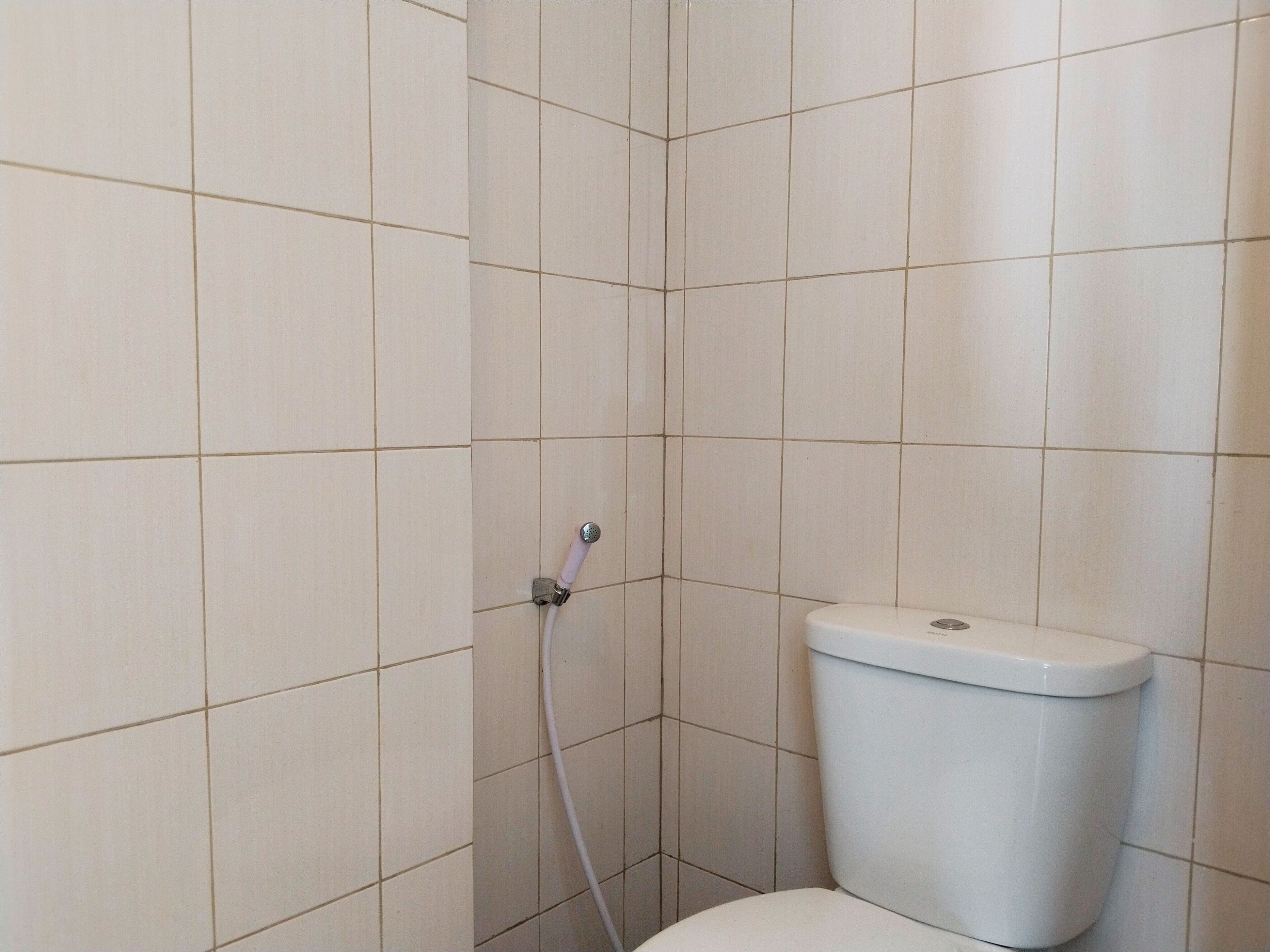 A small, tiled bathroom with a toilet and a shower.