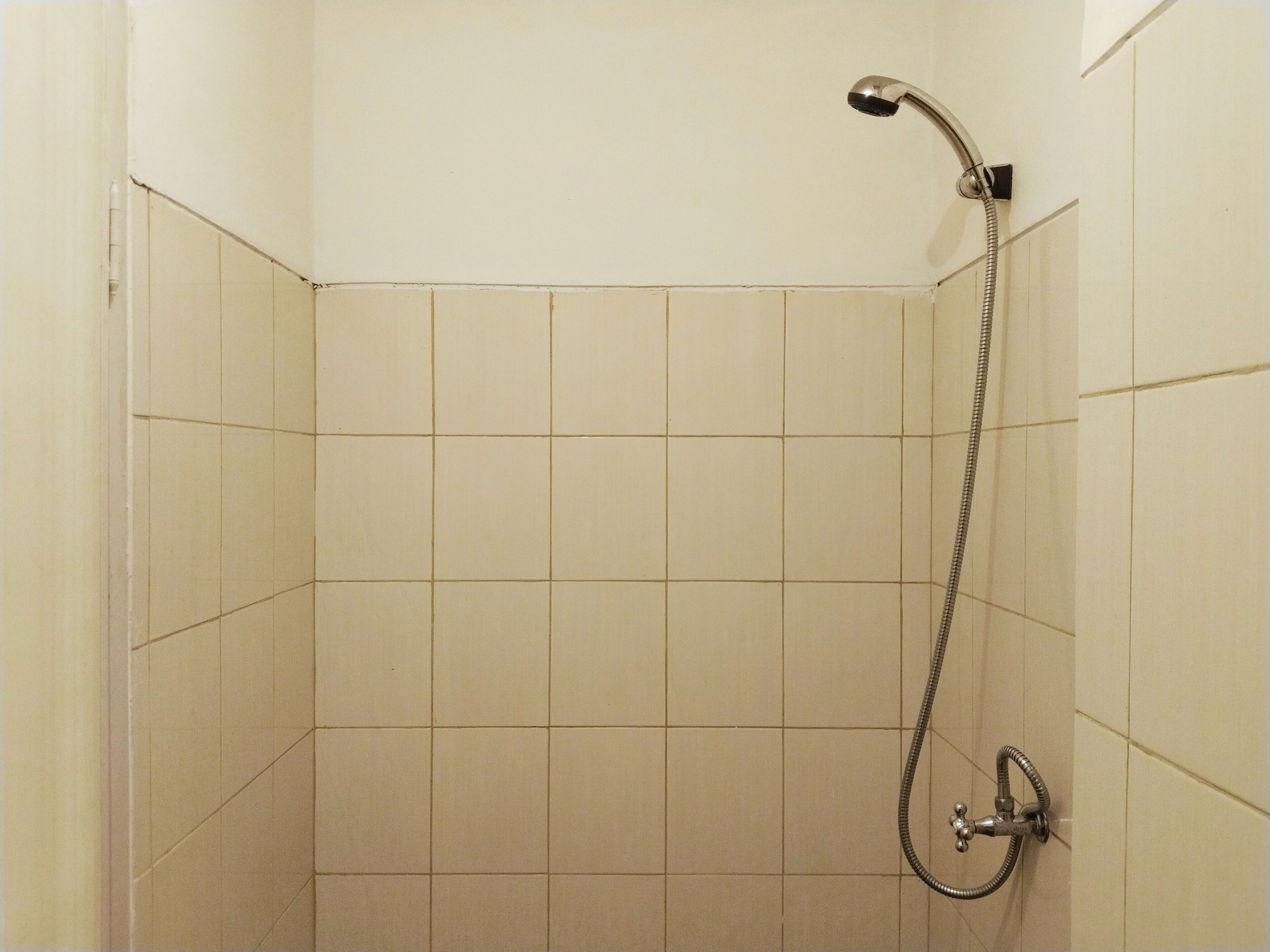A shower with a handheld showerhead and a wall-mounted faucet.