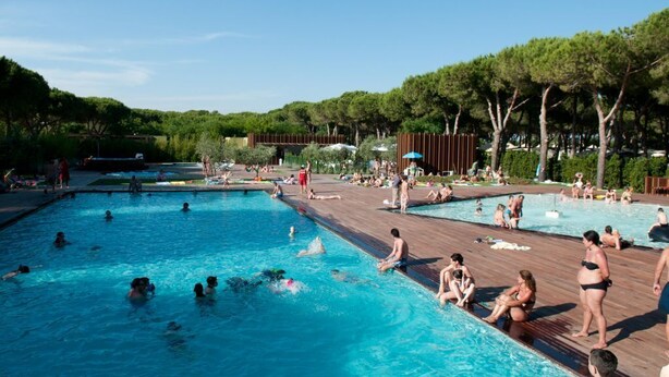 Un área de piscina con varias piscinas y una terraza de madera.