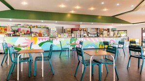 A restaurant with colorful murals, teal chairs, and a variety of food and drink items on display. - Vacation Village California Superior Vulci Cottage for 4 persons (Montalto Marina)