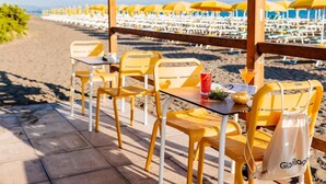 A beachside restaurant with yellow chairs and tables, a wooden pergola, and beach umbrellas in the background. - Vacation Village California Superior Vulci Cottage for 4 persons (Montalto Marina)